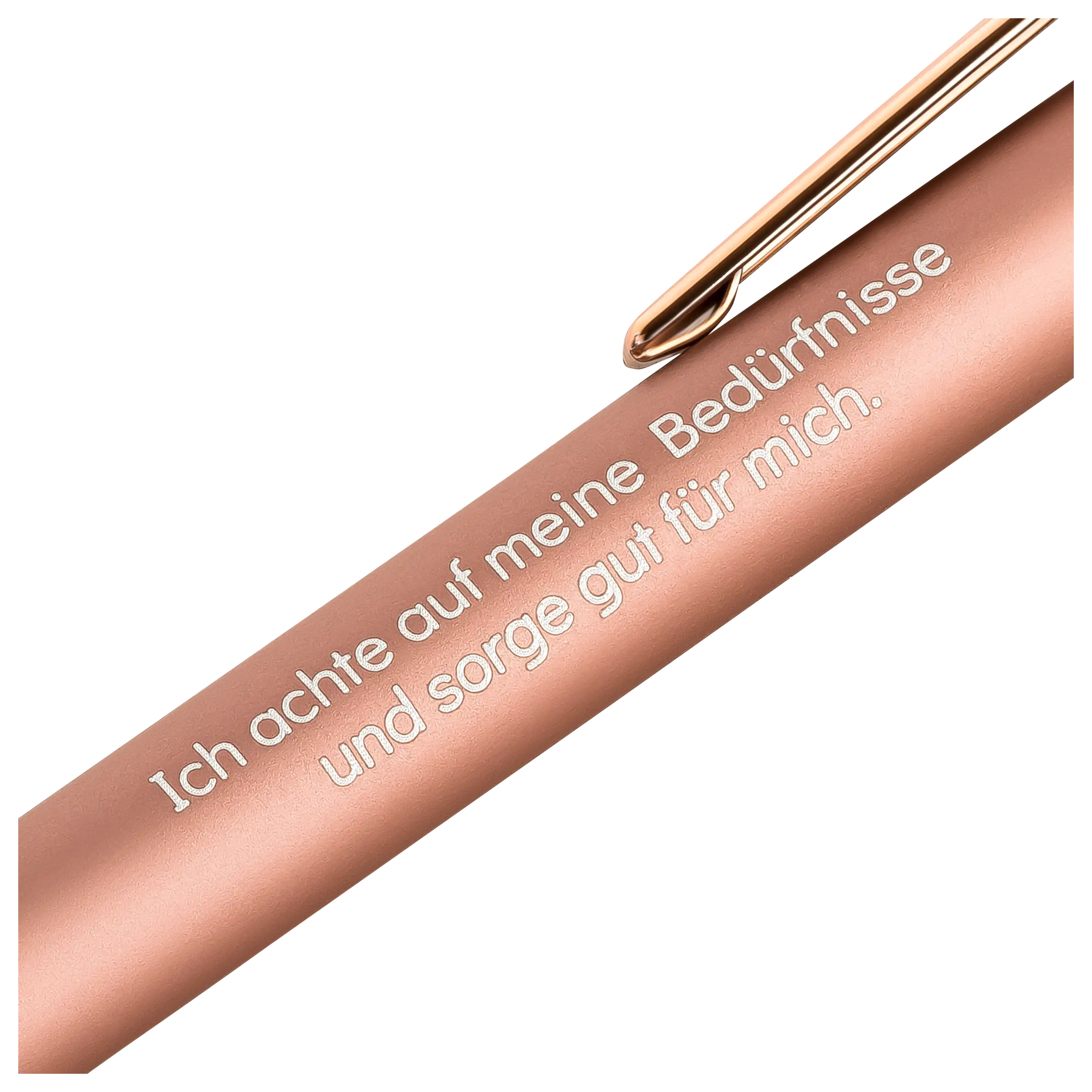 Nahaufnahme eines roségoldenen Stifts mit der Gravur Ich achte auf meine Bedürfnisse und sorge gut für mich.