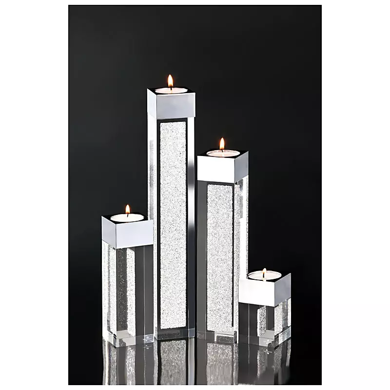 Vier moderne Kerzenhalter aus Glas und Metall mit glitzernden Einsätzen und brennenden Teelichtern vor einem schwarzen Hintergrund von PRO-ducto GmbH.