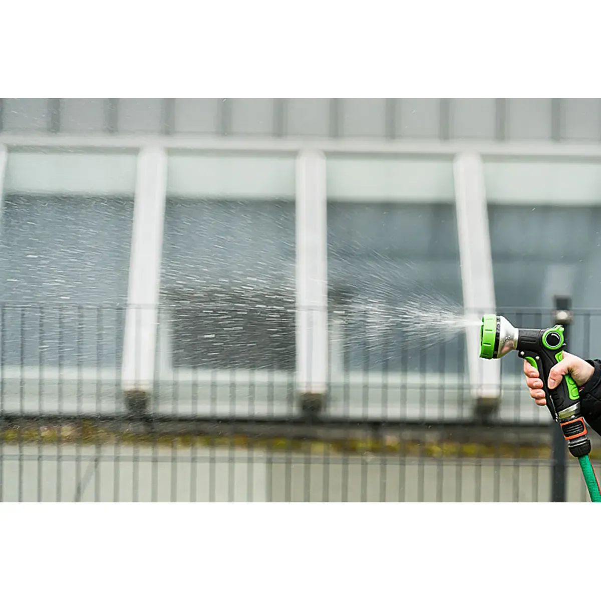 Eine Hand hält eine grüne Gartenspritze, die Wasser versprüht. Professionelle Produktfotos und hochwertige Produktbilder erstellen lassen für Gartenbedarf. PRO-ducto GmbH