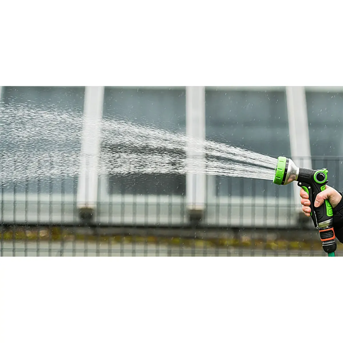 Hand hält eine grüne Gartenspritze, die Wasser versprüht. Professionelle Produktfotos und Freisteller für hochwertige Produktbilder erstellen lassen. PRO-ducto GmbH