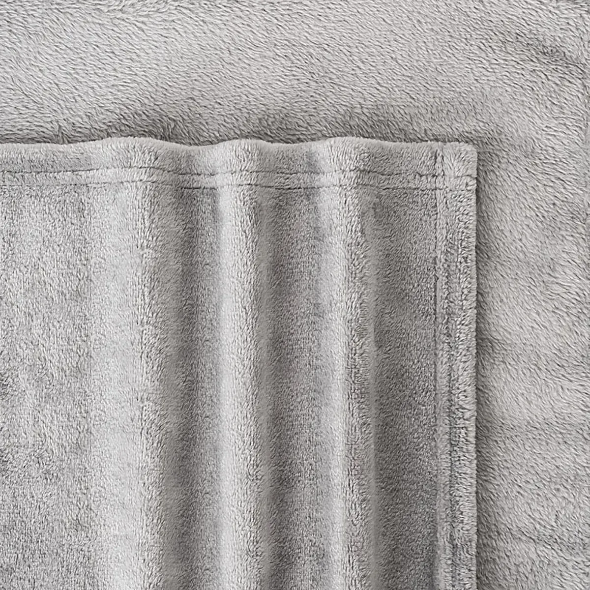 Nahaufnahme einer grauen Fleecedecke für professionelle Produktfotografie. Textilfotografie zeigt die weiche Struktur und die saubere Saumnaht. PRO-ducto GmbH