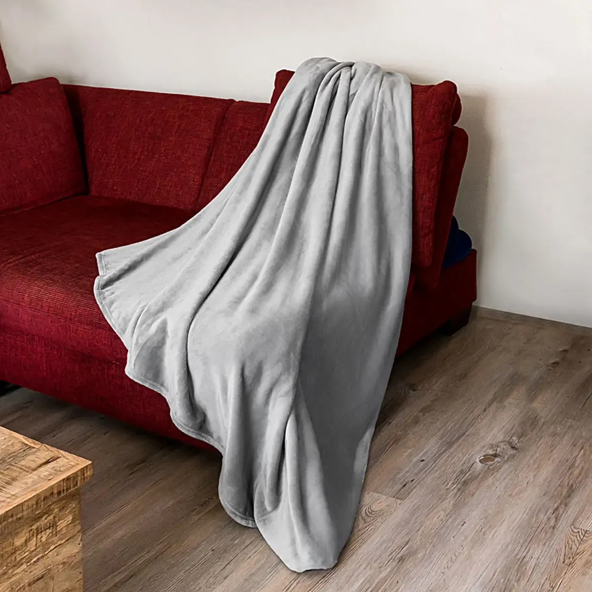 Professionelle Produktfotografie einer grauen Kuscheldecke auf einem roten Sofa. Hochwertige Textilfotografie für ansprechende Produktbilder. PRO-ducto GmbH